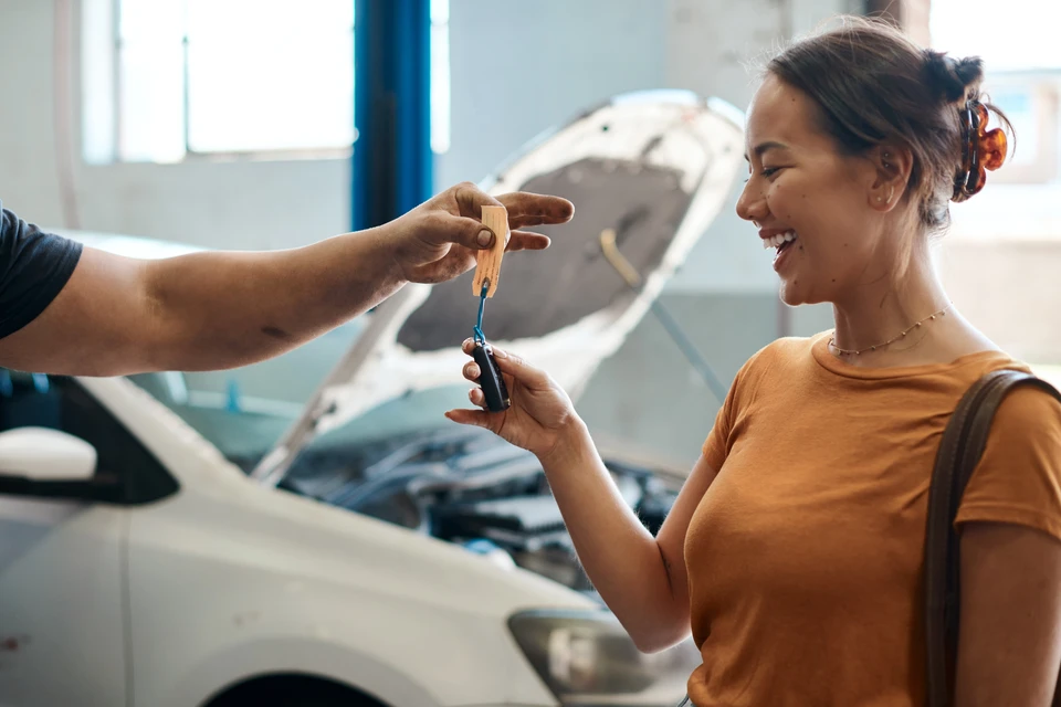 Scène intérieure d'un atelier automobile avec deux personnes échangeant des clés de véhicule
