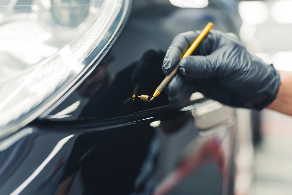 Extérieur automobile, technicien effectuant polissage professionnel phare avant véhicule noir